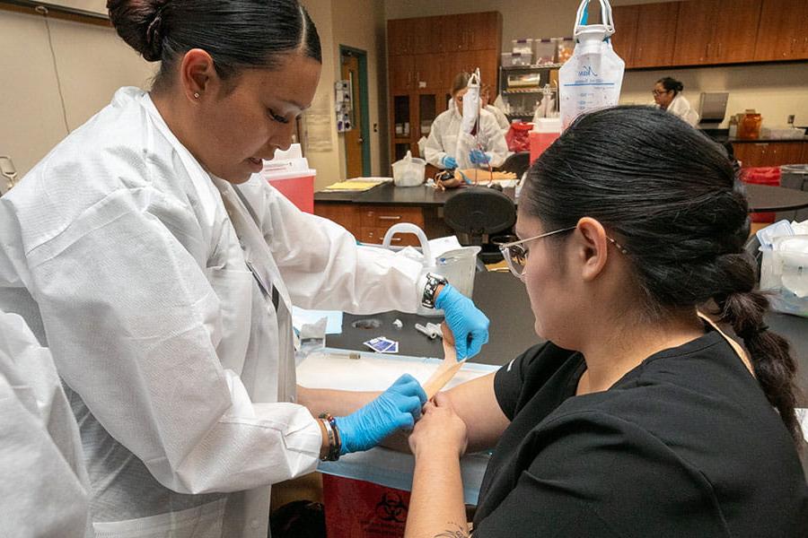 Students practicing drawing blood on another student